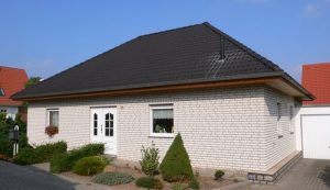 Bungalow Pechau mit dunklem Walmdach und Vorgarten